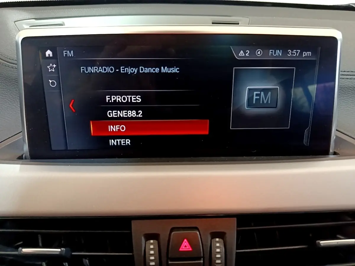 Écran tactile central de la BMW X2 xDrive25e 2020 affichant les stations radio FM dans l'habitacle gris.
