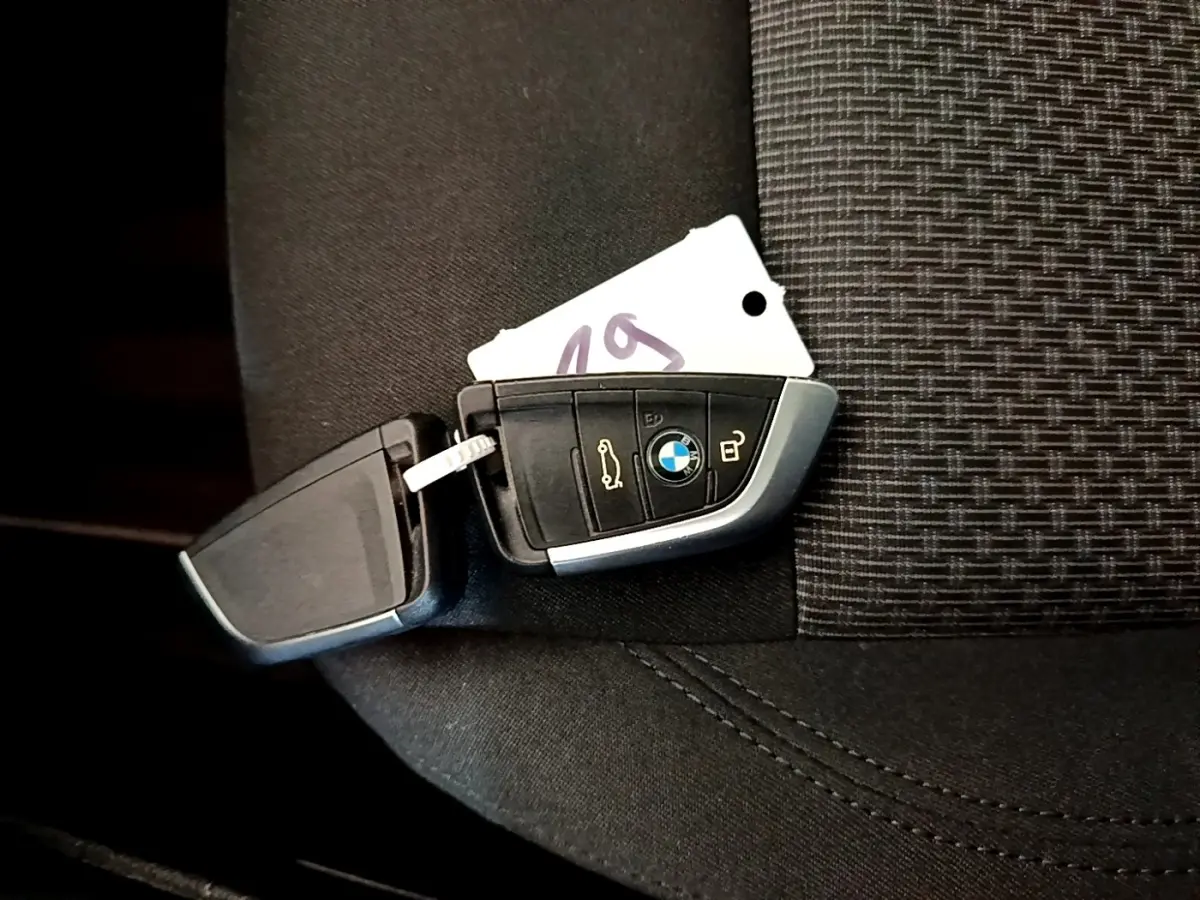 Clé BMW posée sur un siège tissu noir, montrant les boutons de verrouillage et ouverture du coffre.