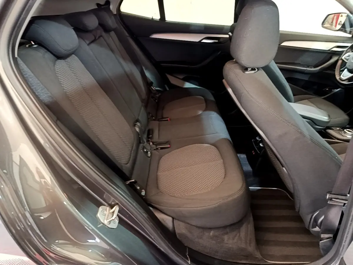 Vue intérieure côté gauche montrant les sièges arrière noirs et le dossier du siège avant d'une BMW X2 hybride rechargeable.