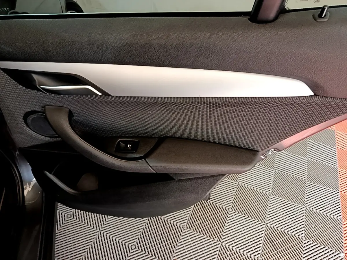 Gros plan sur la porte intérieure côté gauche de la BMW X2 hybride rechargeable, avec poignée noire et insert argenté.