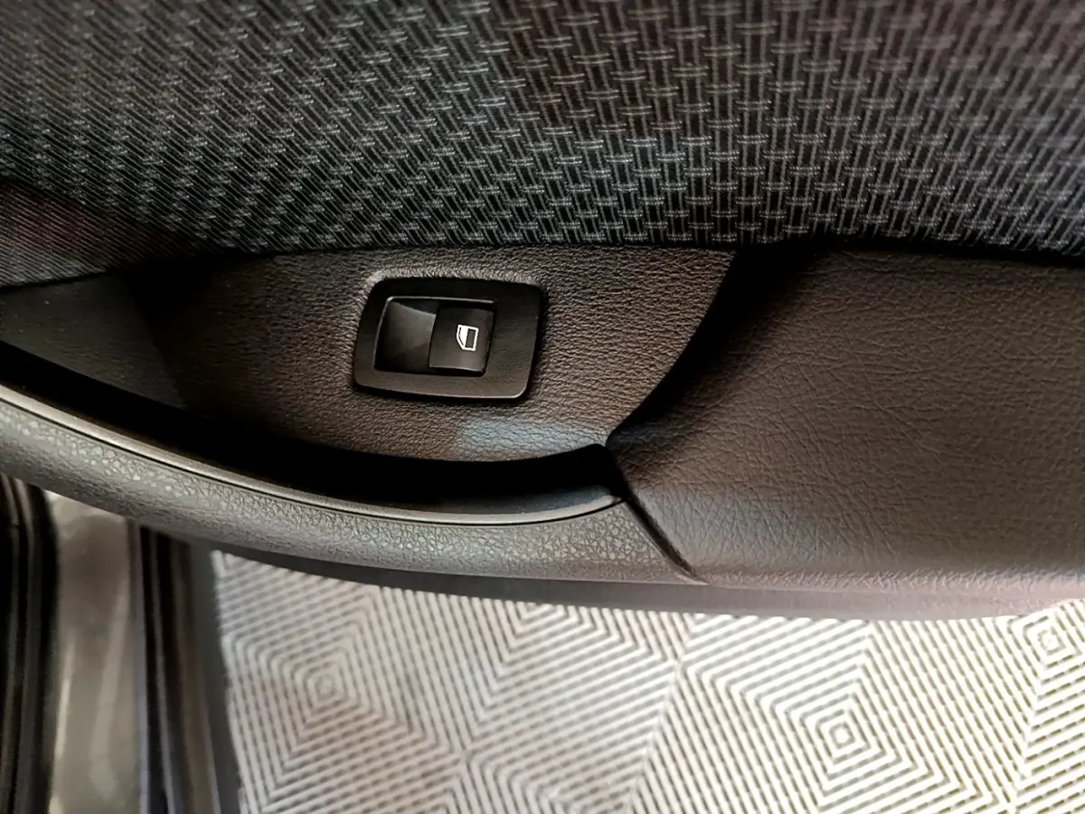 Bouton de commande de lève-vitre sur la porte intérieure en cuir noir du BMW X2 xDrive25e, vue rapprochée.