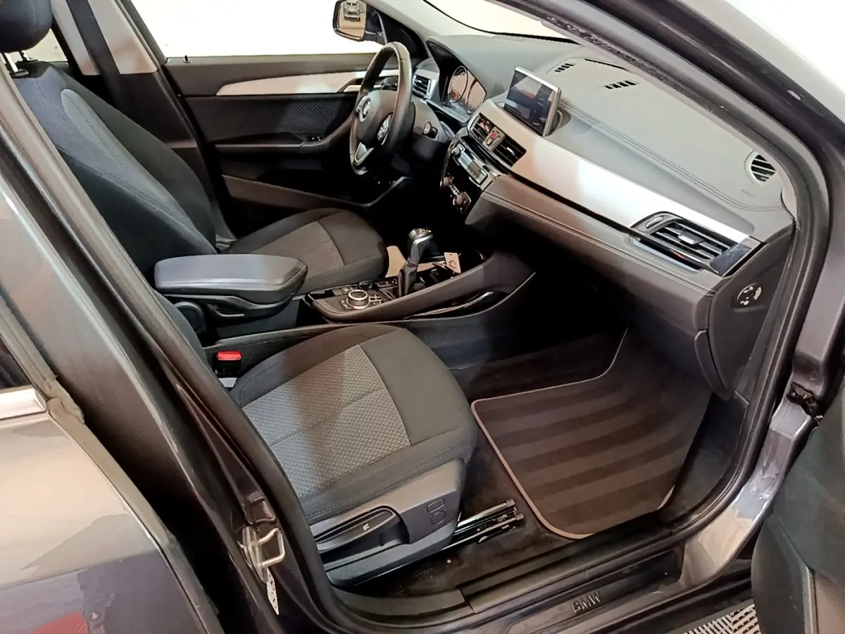Vue intérieure côté conducteur de la BMW X2 hybride rechargeable 2020, sièges tissu gris et tableau de bord moderne.