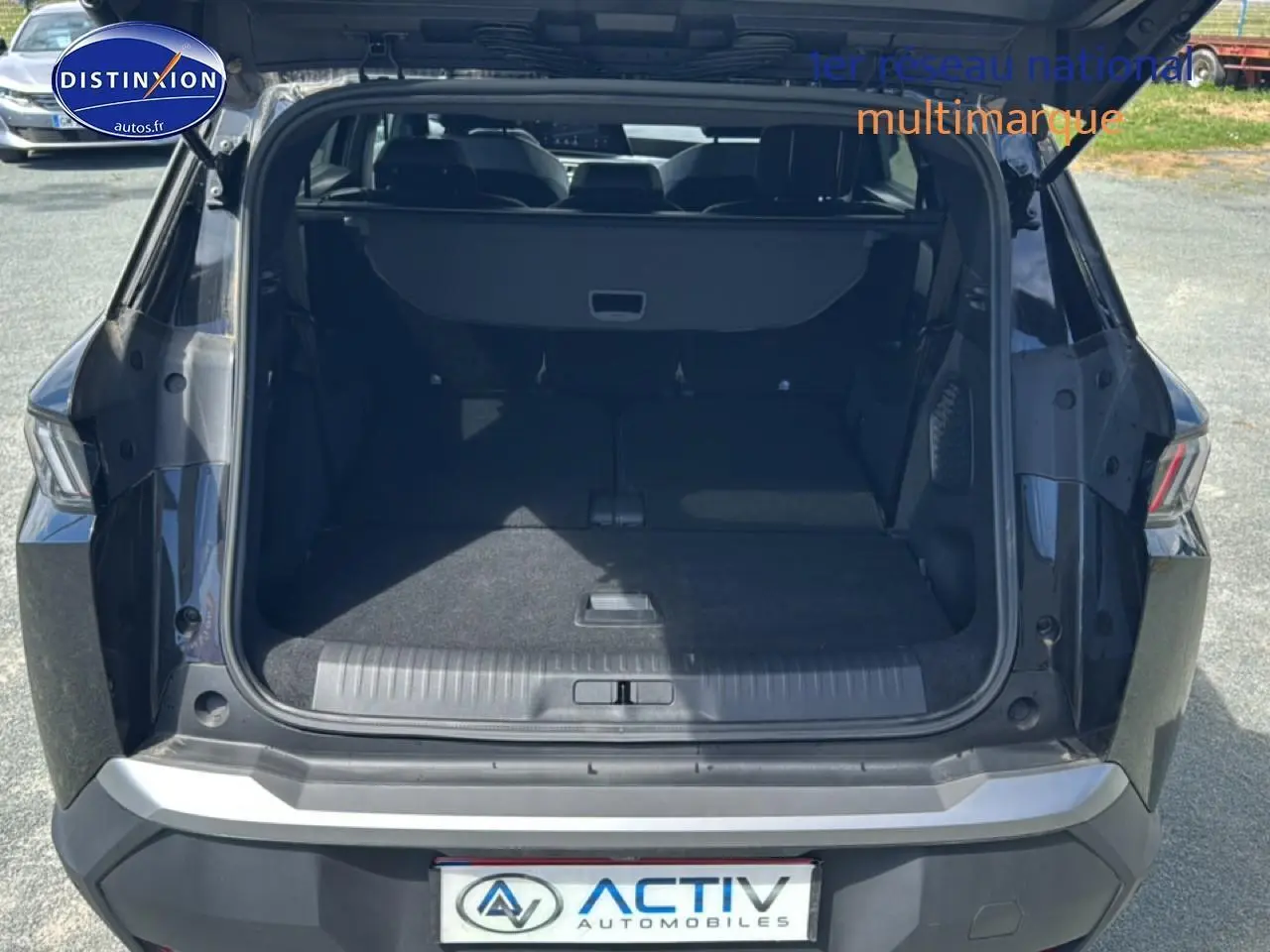 Coffre ouvert vu de l'arrière d'un Peugeot 5008 Hybrid 145 allure noir, montrant l'espace de chargement et la banquette arrière.
