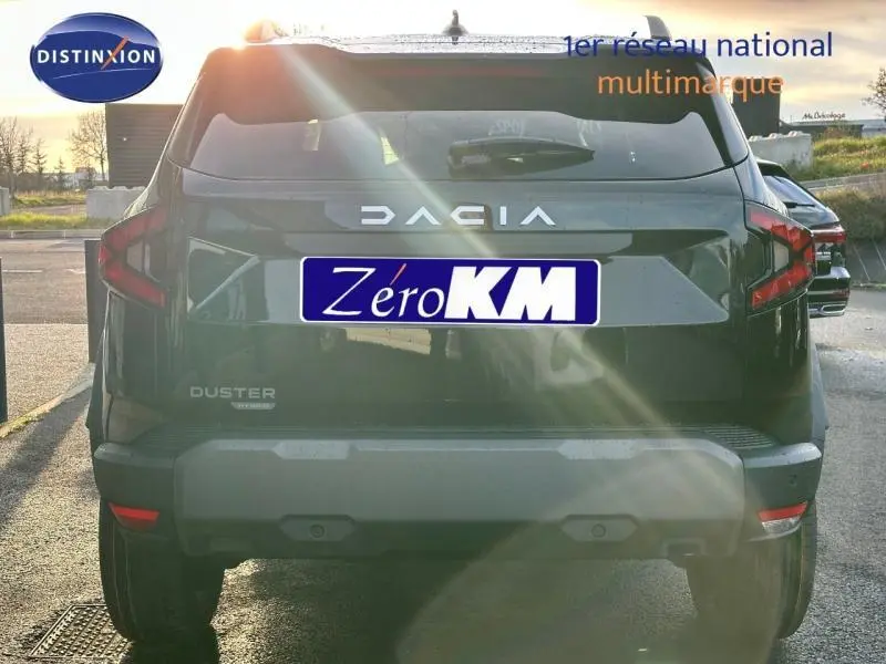 Vue arrière d'un Dacia Duster 2025 noir nacré métallisé avec logo distinctif et plaque Zéro KM en plein soleil.
