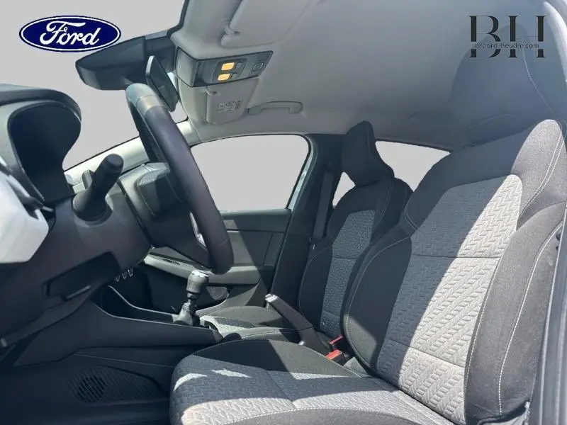 Intérieur avant de la Renault Clio 2023, vue côté conducteur, sièges tissu noir à motifs surpiqués.