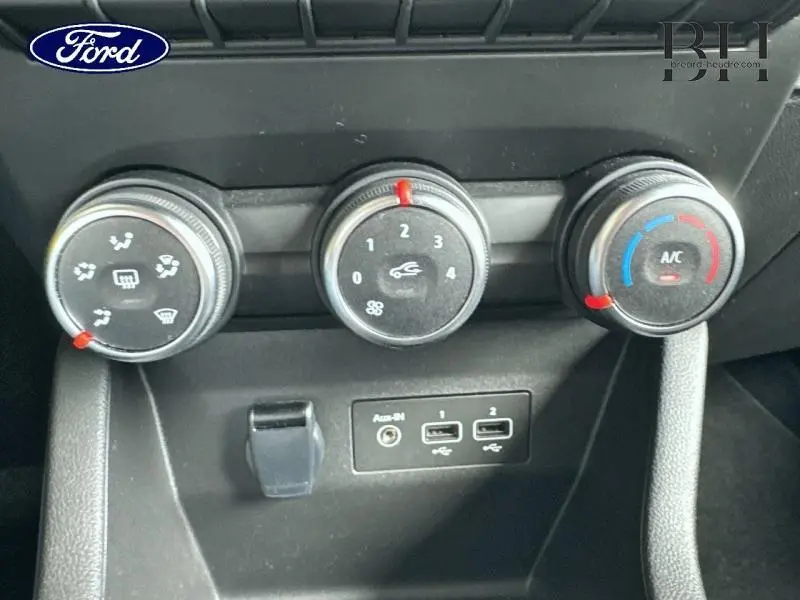 Gros plan sur les commandes de climatisation manuelle et les ports USB d'une Renault Clio blanche, version Business GPL 2023.