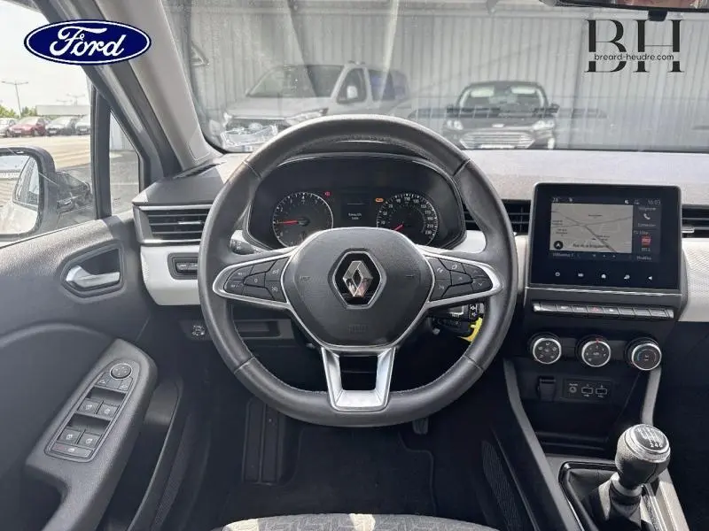 Vue intérieure frontale du volant Renault Clio blanc avec tableau de bord numérique et écran tactile central.