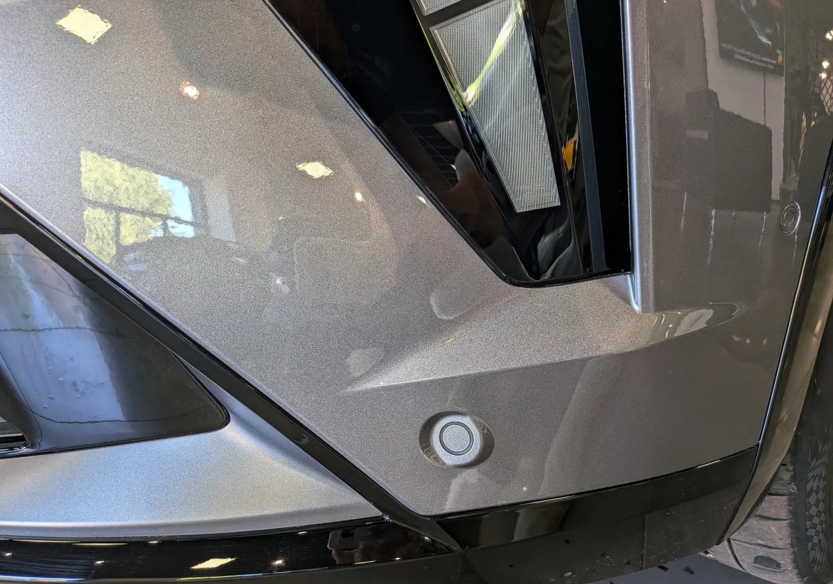 Gros plan sur le pare-chocs avant gris schiste du Renault Rafale, mettant en valeur le capteur de stationnement et le feu LED.