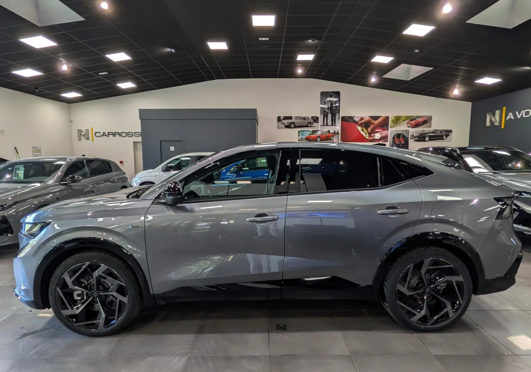 Profil droit du Renault Rafale gris schiste hyper hybrid E-Tech 300 ch avec jantes noires en showroom.