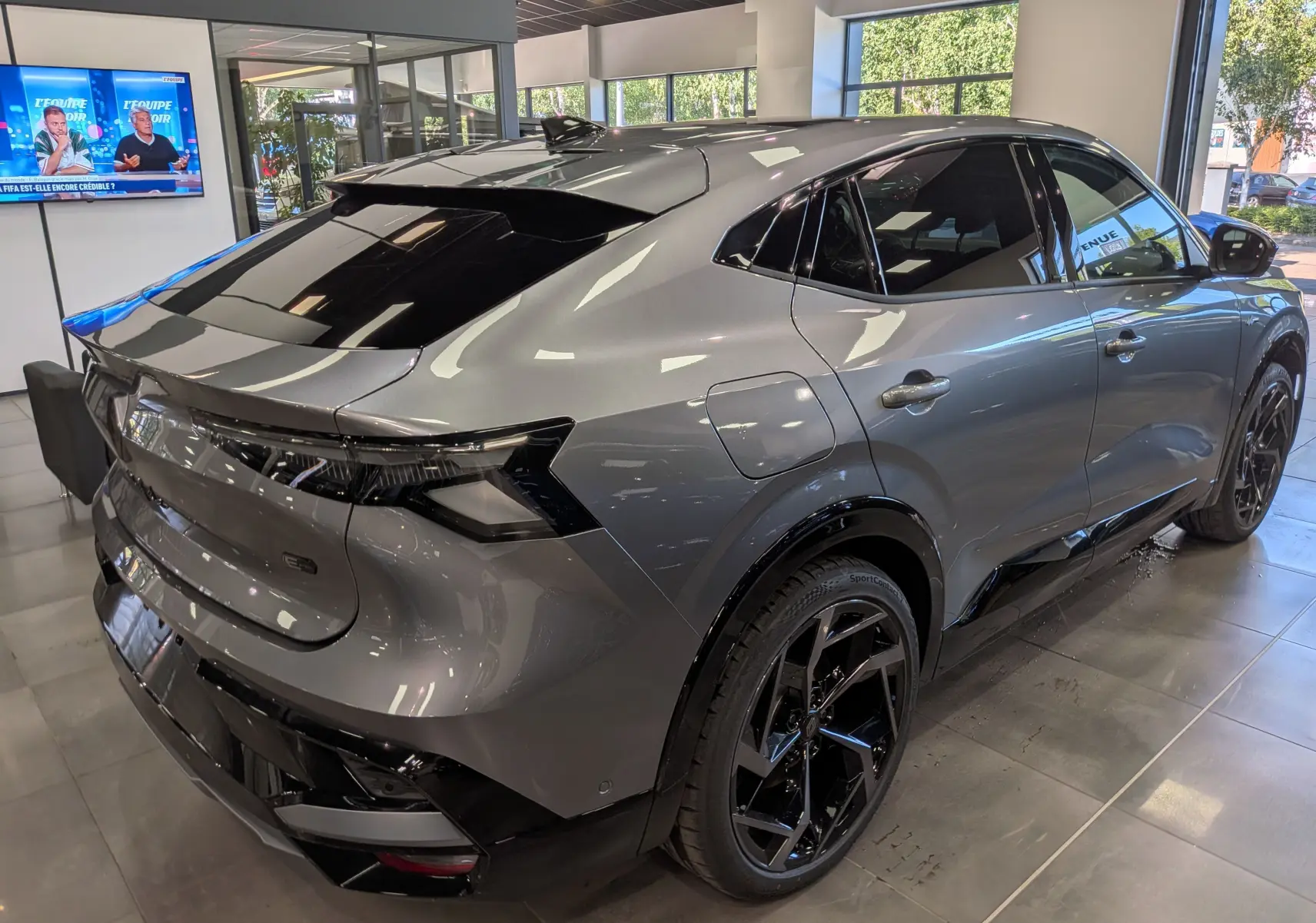 Vue 3/4 arrière droite du Renault Rafale gris schiste avec jantes noires brillantes dans un showroom.