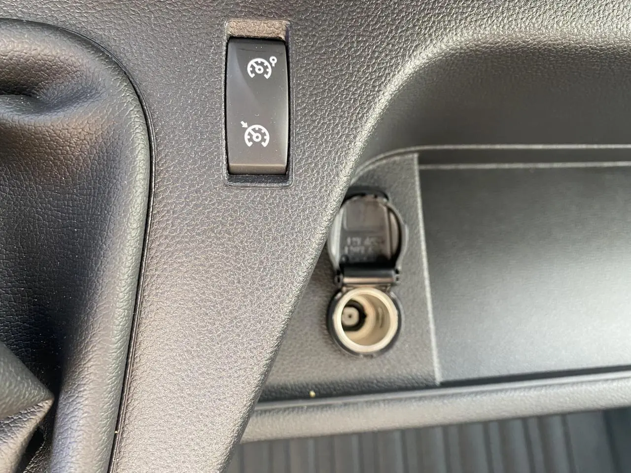Prise 12 volts ouverte et bouton de régulateur de vitesse sur la console noire du Nissan Interstar blanc 2022.