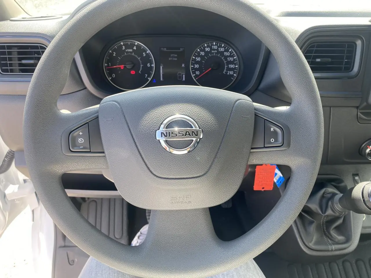 Vue centrée sur le volant Nissan du tableau de bord du fourgon blanc Interstar, avec commandes au volant et levier de vitesse manuel.