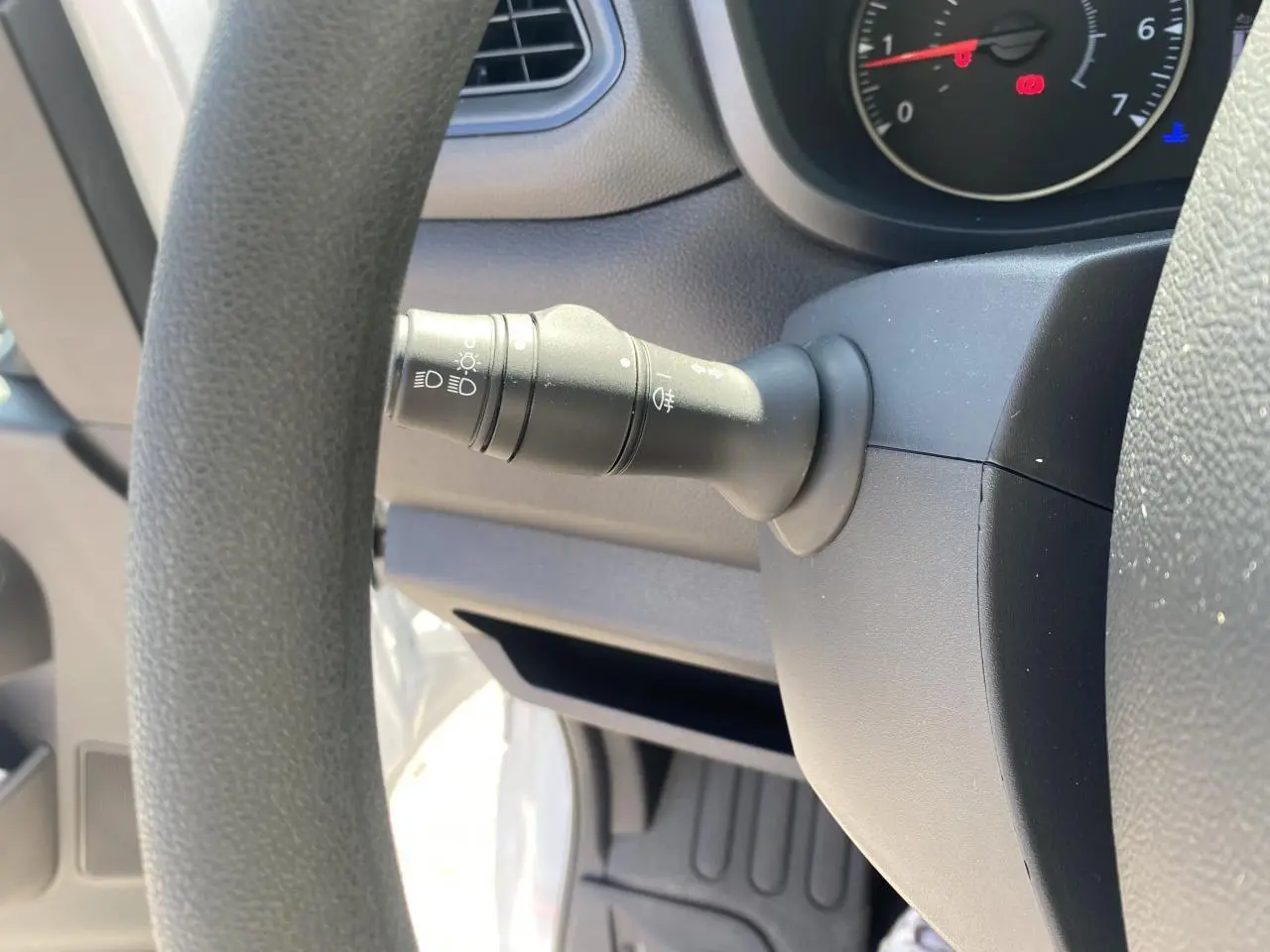 Gros plan sur la manette d'éclairage à gauche du volant dans un Nissan Interstar blanc, tableau de bord partiel visible.