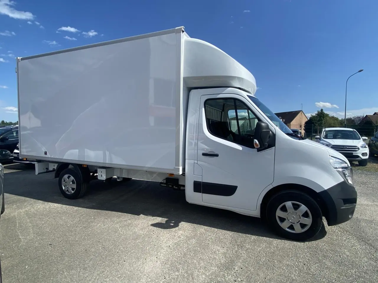 Vue de profil côté droit d'un utilitaire blanc Nissan Interstar Acenta 2022 avec capucine sur parking en extérieur.