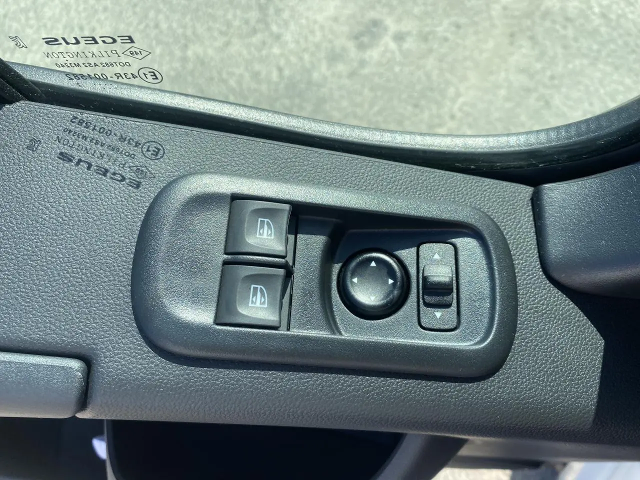 Gros plan sur les commandes des lève-vitres et réglage des rétroviseurs côté conducteur du Nissan Interstar blanc 2022.