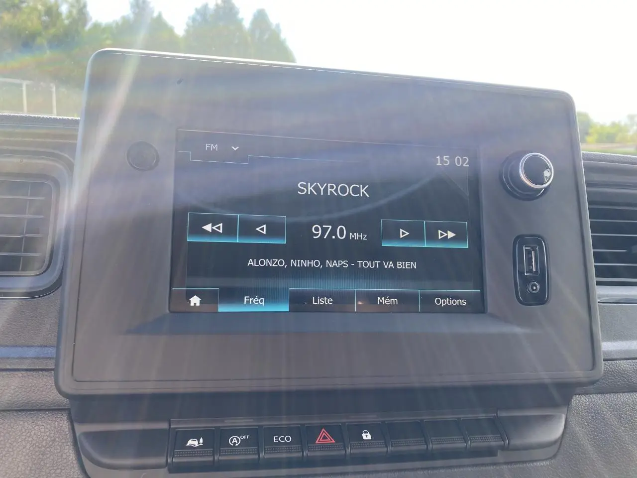 Écran tactile du système NissanConnect affichant la radio FM sur un tableau de bord noir du Nissan Interstar blanc 2022.