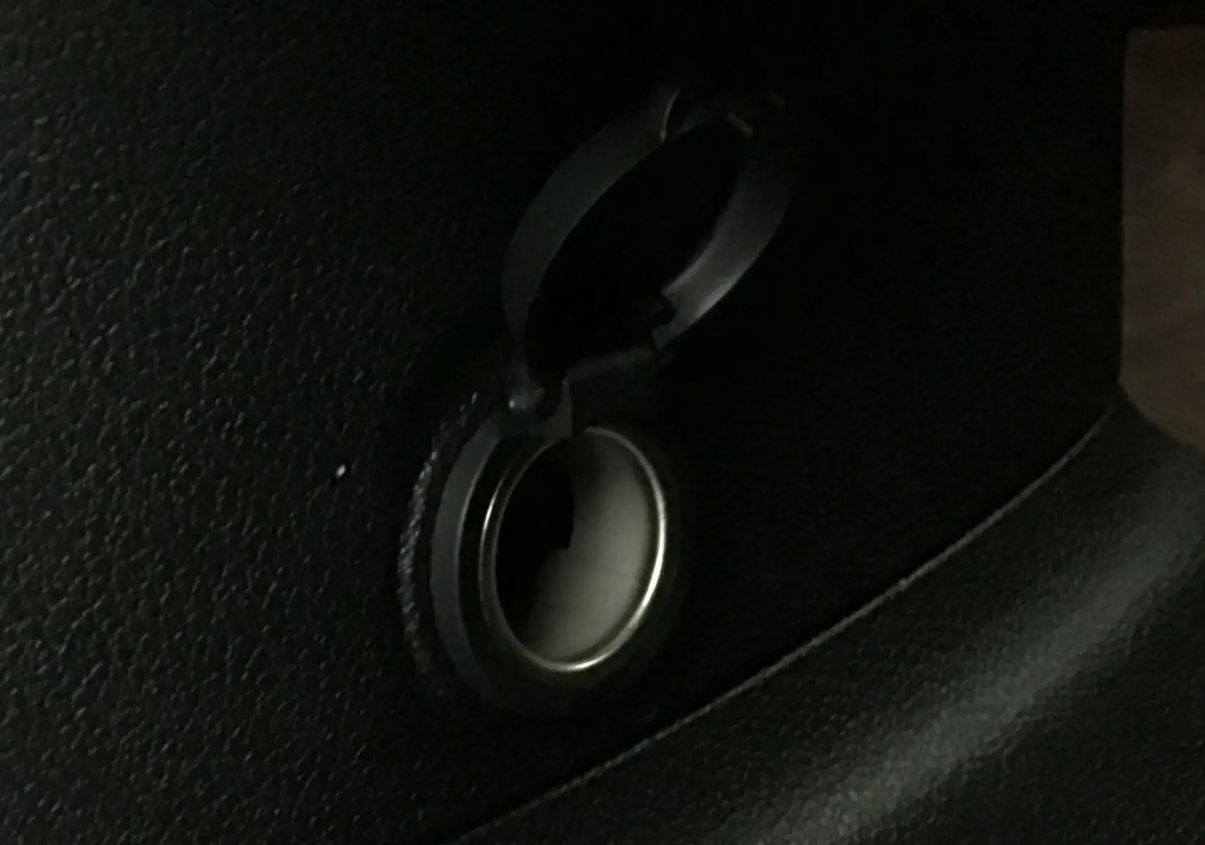 Prise 12V noire ouverte sur le panneau intérieur d'un Peugeot Partner blanc, vue en gros plan.