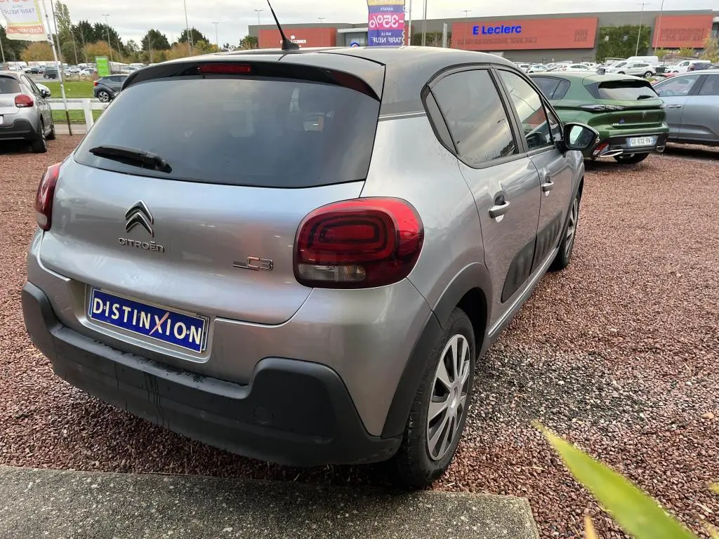 Citroën C3 gris foncé vue 3/4 arrière droit, avec adhésifs Origins sur portes et toit noir contrasté.