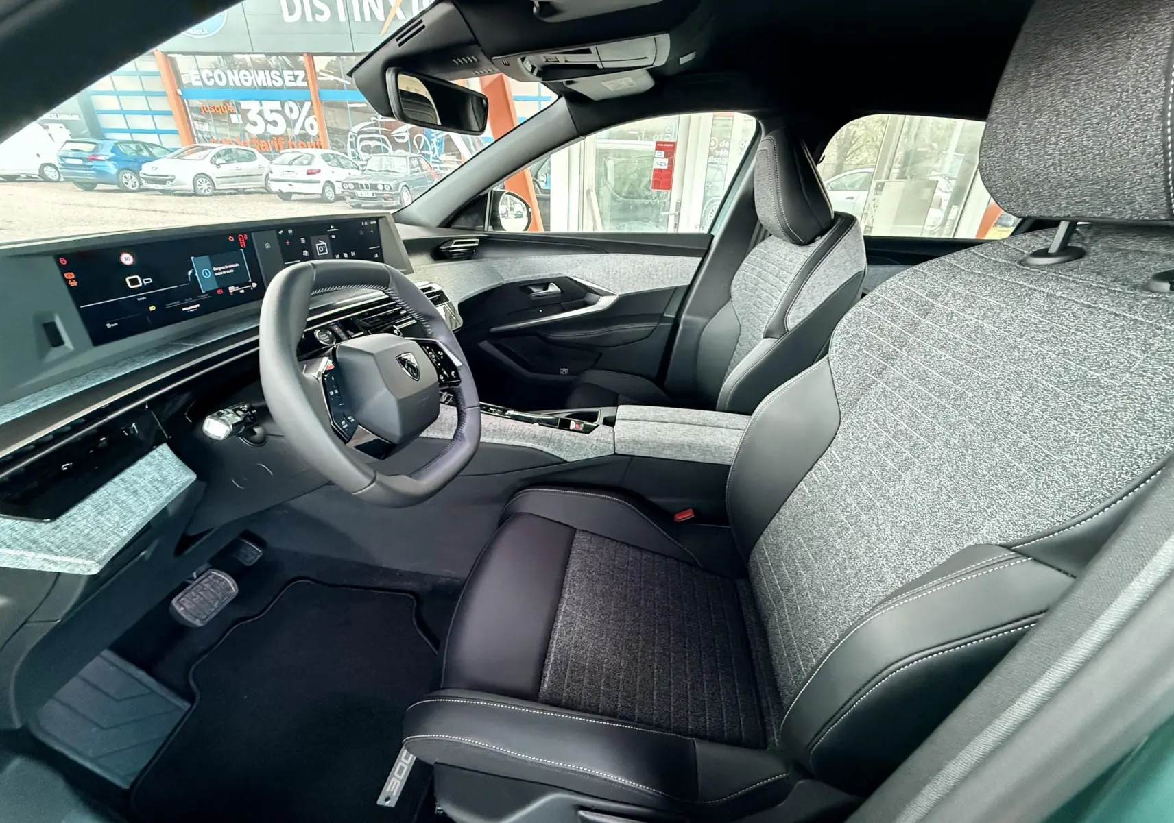 Intérieur avant droit du Peugeot 3008 Hybrid 2025 avec sièges tissu et cuir, tableau de bord numérique et volant compact.