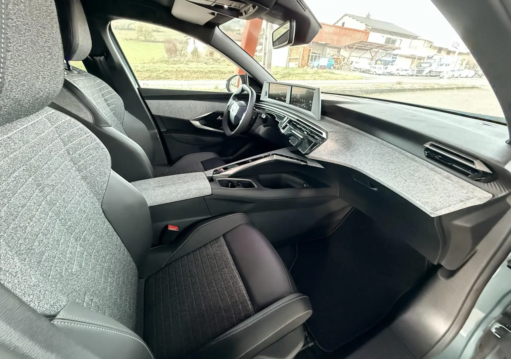 Intérieur du Peugeot 3008 Hybrid 2025 vu côté passager, avec sièges gris et tableau de bord clair moderne.