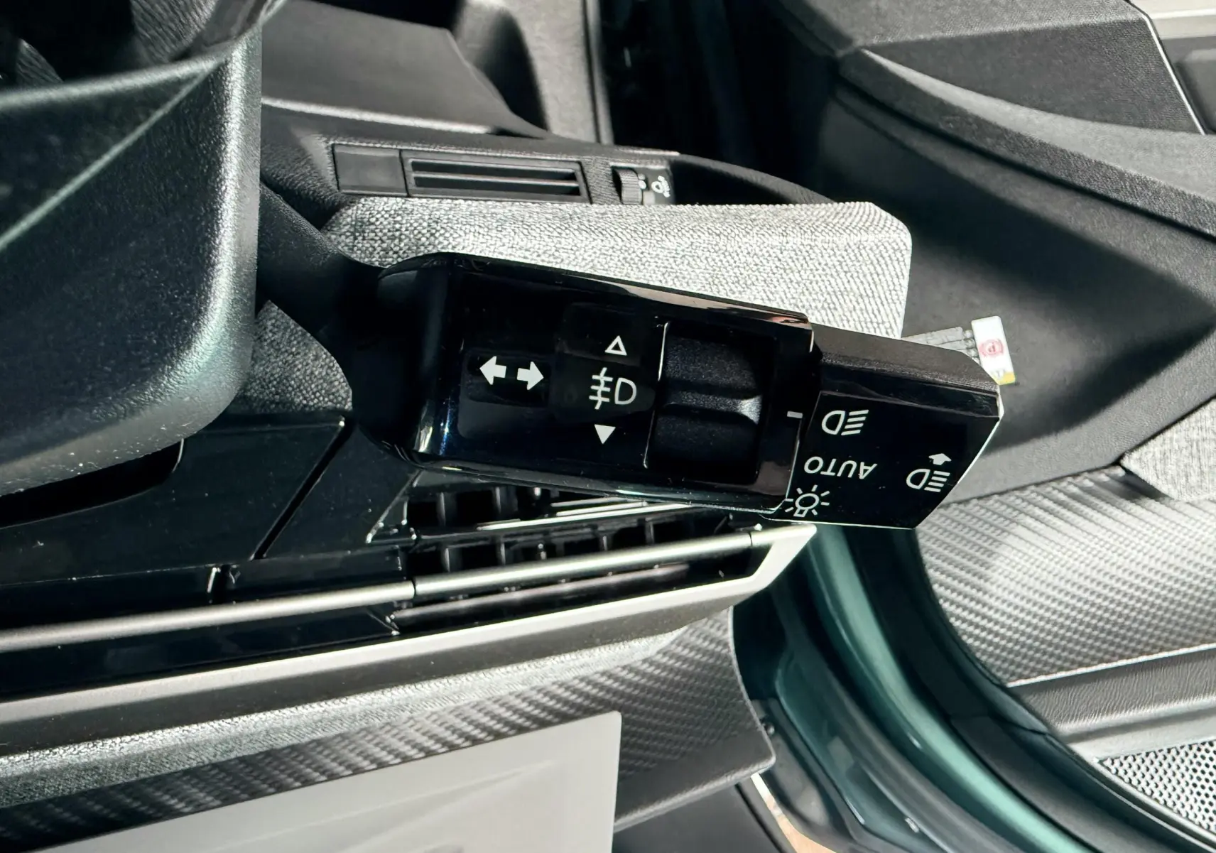Gros plan sur la commande des phares et clignotants du Peugeot 3008 Hybrid 2025, intérieur gris et bleu Ingaro Metal visible.