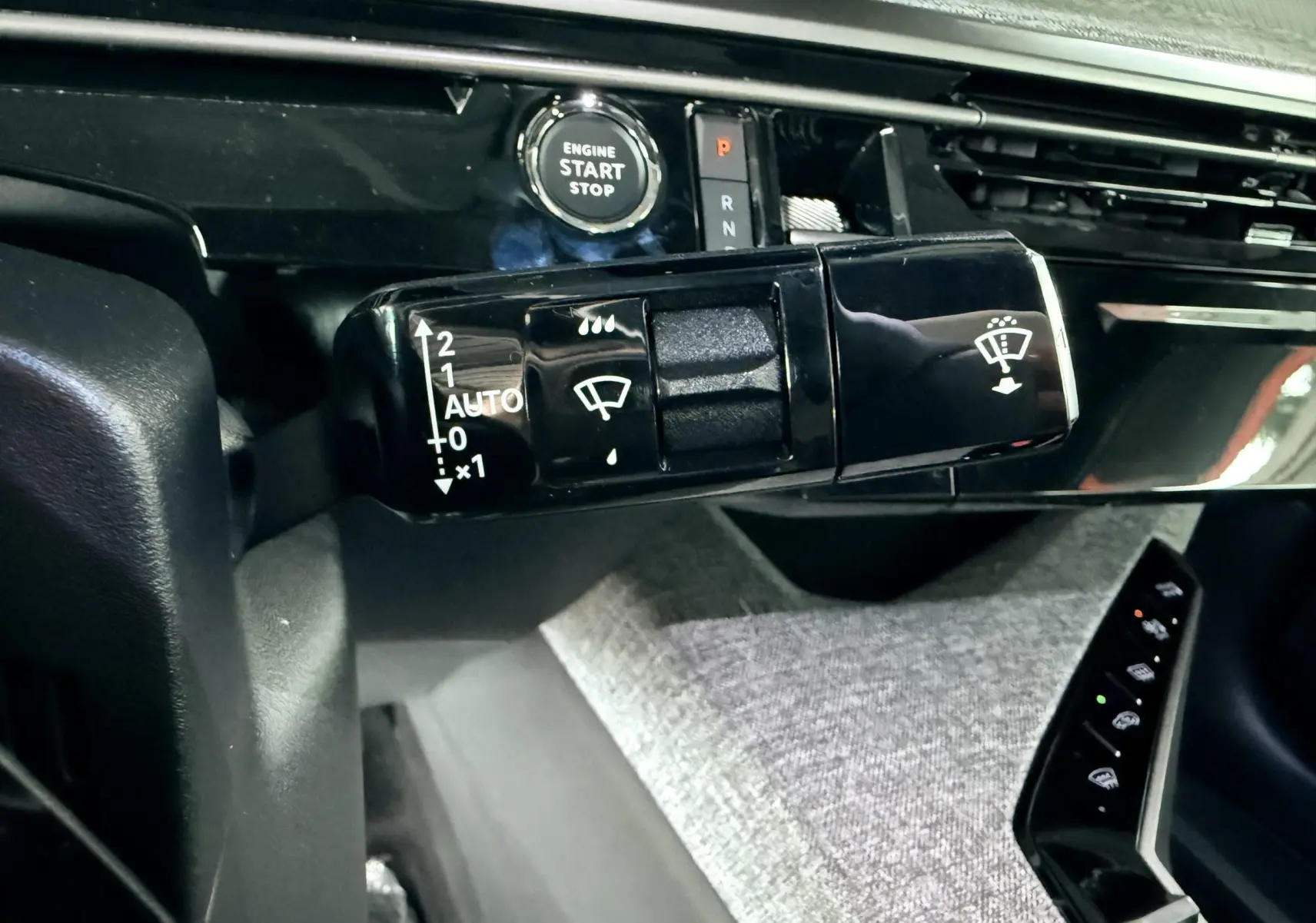 Gros plan sur la commande d'essuie-glace et le bouton start/stop du tableau de bord du Peugeot 3008 Hybrid 2025.