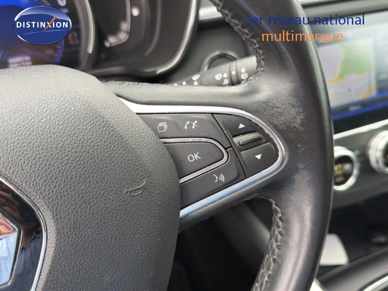 Gros plan sur le volant en cuir noir du Renault Kadjar 2021, avec commandes intégrées et tableau de bord flou en arrière-plan.