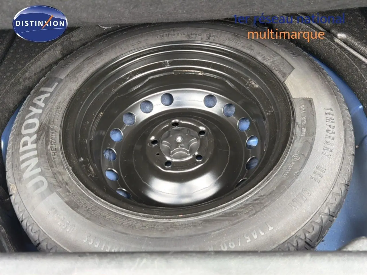Roue de secours noire montée sur jante acier, logée dans le coffre d’un Renault Kadjar bleu Iron.