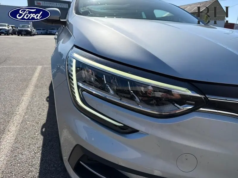 Gros plan sur le phare avant gauche d'une Renault Mégane gris Highland, mettant en valeur son éclairage LED distinctif.