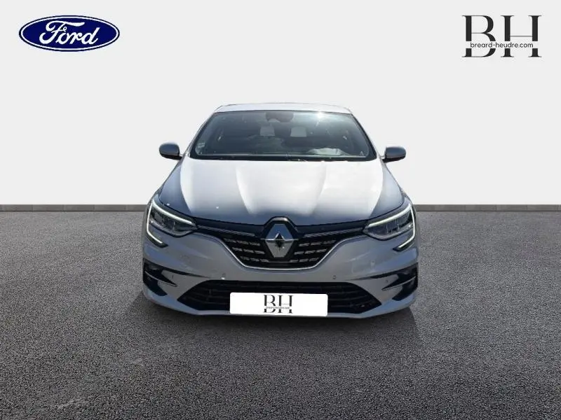 Vue frontale d'une Renault Mégane gris Highland 2023 avec calandre noire et logo Renault central bien visible.