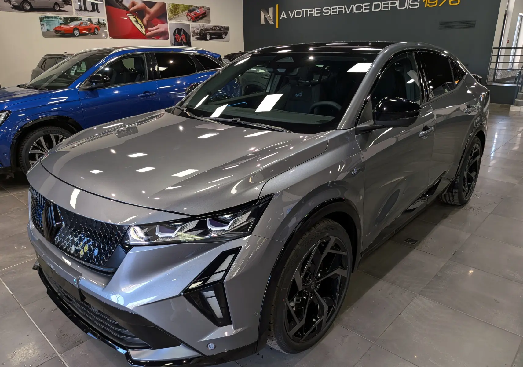 Vue 3/4 avant droit du Renault Rafale gris schiste avec jantes noires et signature lumineuse distinctive en showroom.