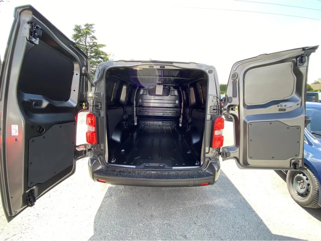 Vue arrière ouverte du Peugeot Expert Fourgon gris platinium 2022 montrant l'espace de chargement tôlé et vide.