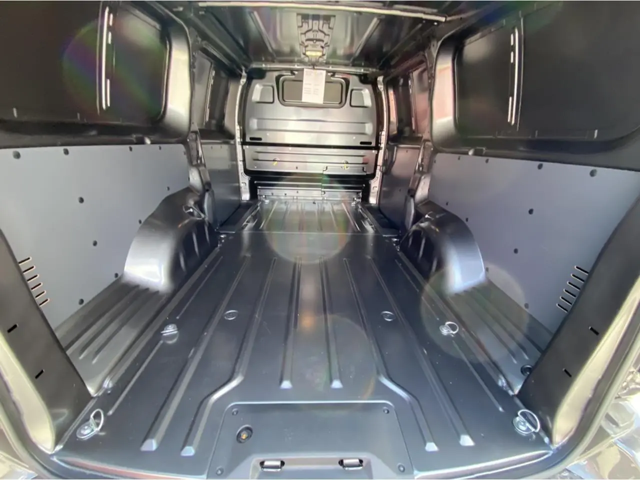 Vue intérieure du coffre du Peugeot Expert Fourgon gris platinium, montrant l'espace de chargement tôlé et les renforts latéraux.
