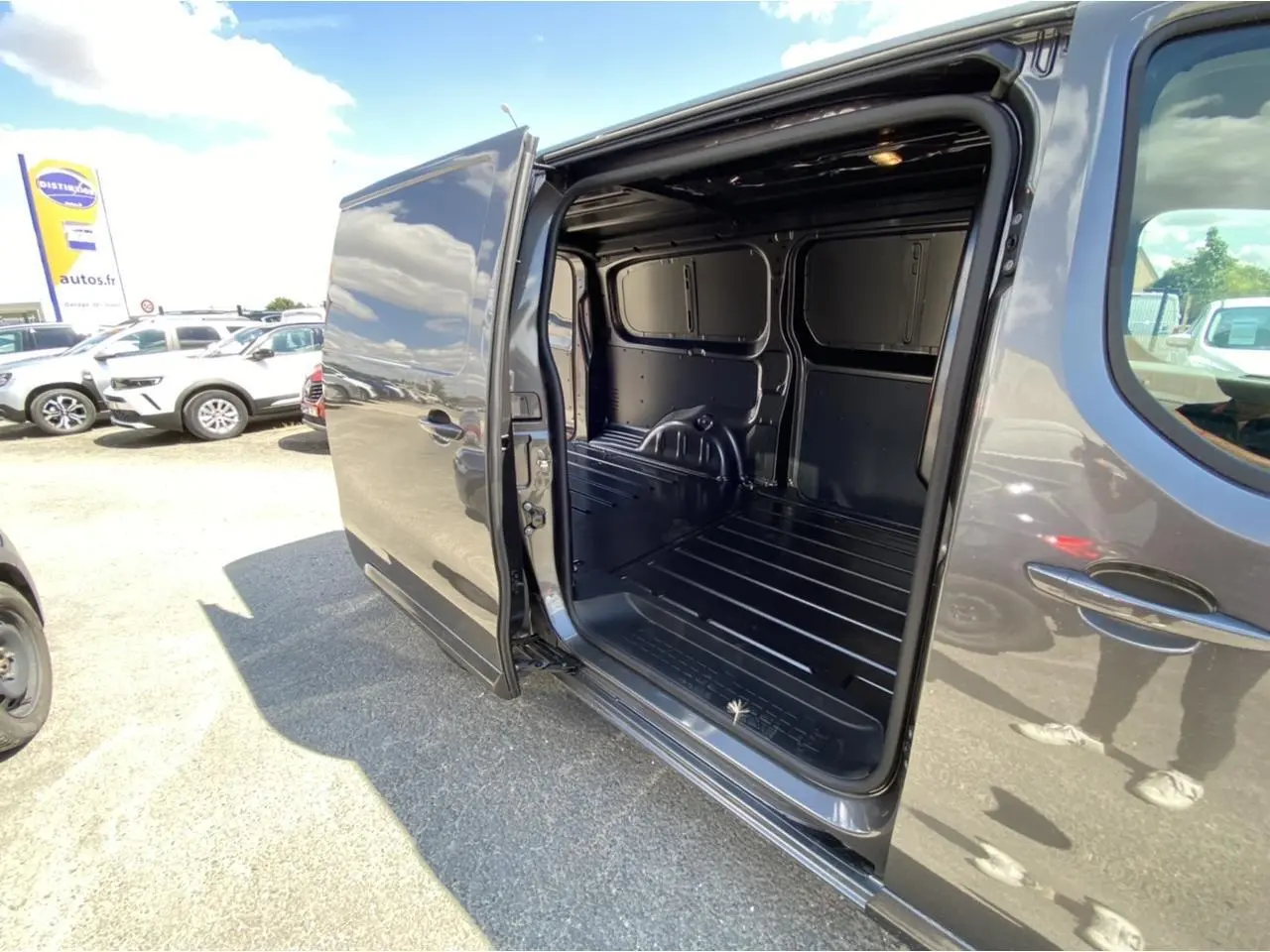 Vue latérale droite d'un Peugeot Expert Fourgon gris platinium avec porte coulissante ouverte montrant l'espace de chargement vide.