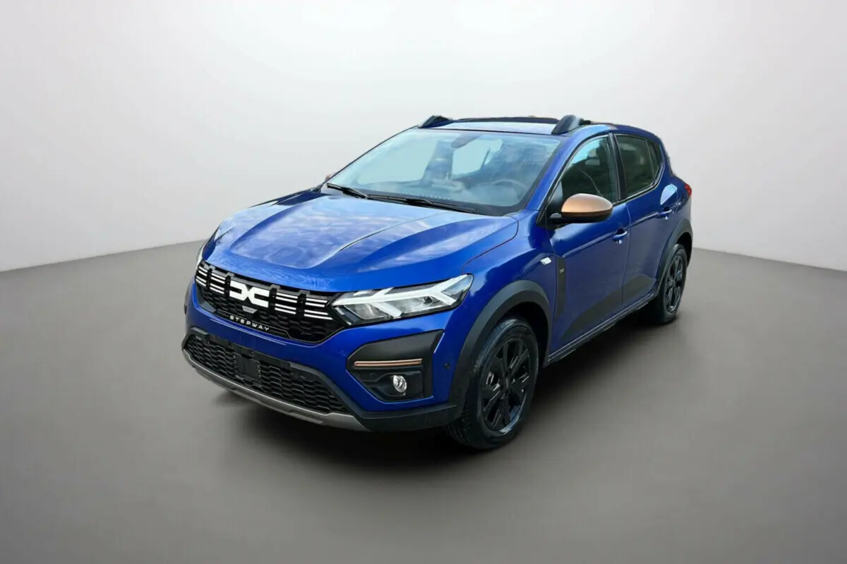 Vue 3/4 avant d'une Dacia Sandero Stepway 2024 bleu iron avec coques de rétroviseurs bronze et jantes noires.