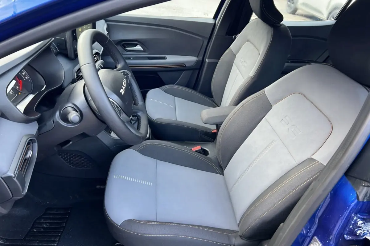 Intérieur de la Dacia Sandero Stepway 2024 en bleu iron, vue côté conducteur avec sièges bi-matière gris clair et foncé.