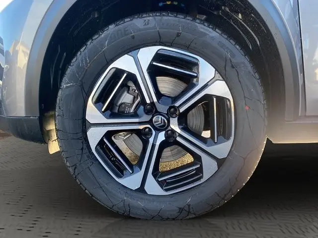 Gros plan sur la roue avant gauche du Citroën C3 Aircross Hybrid 145 gris Mercury avec jante alliage noire et argentée.