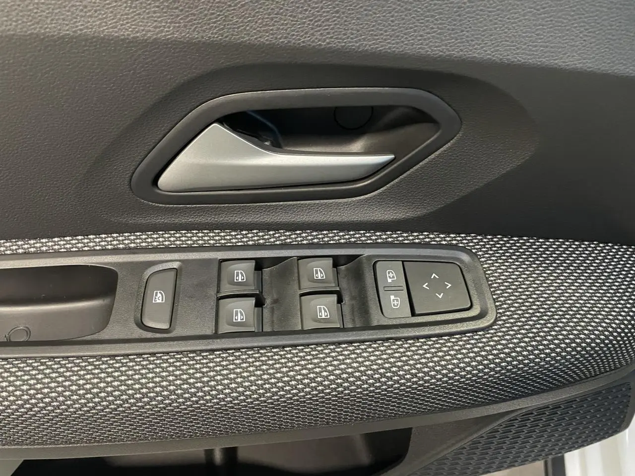 Gros plan sur la commande des vitres électriques côté gauche d'une Dacia Sandero Stepway blanc glacier 2025.
