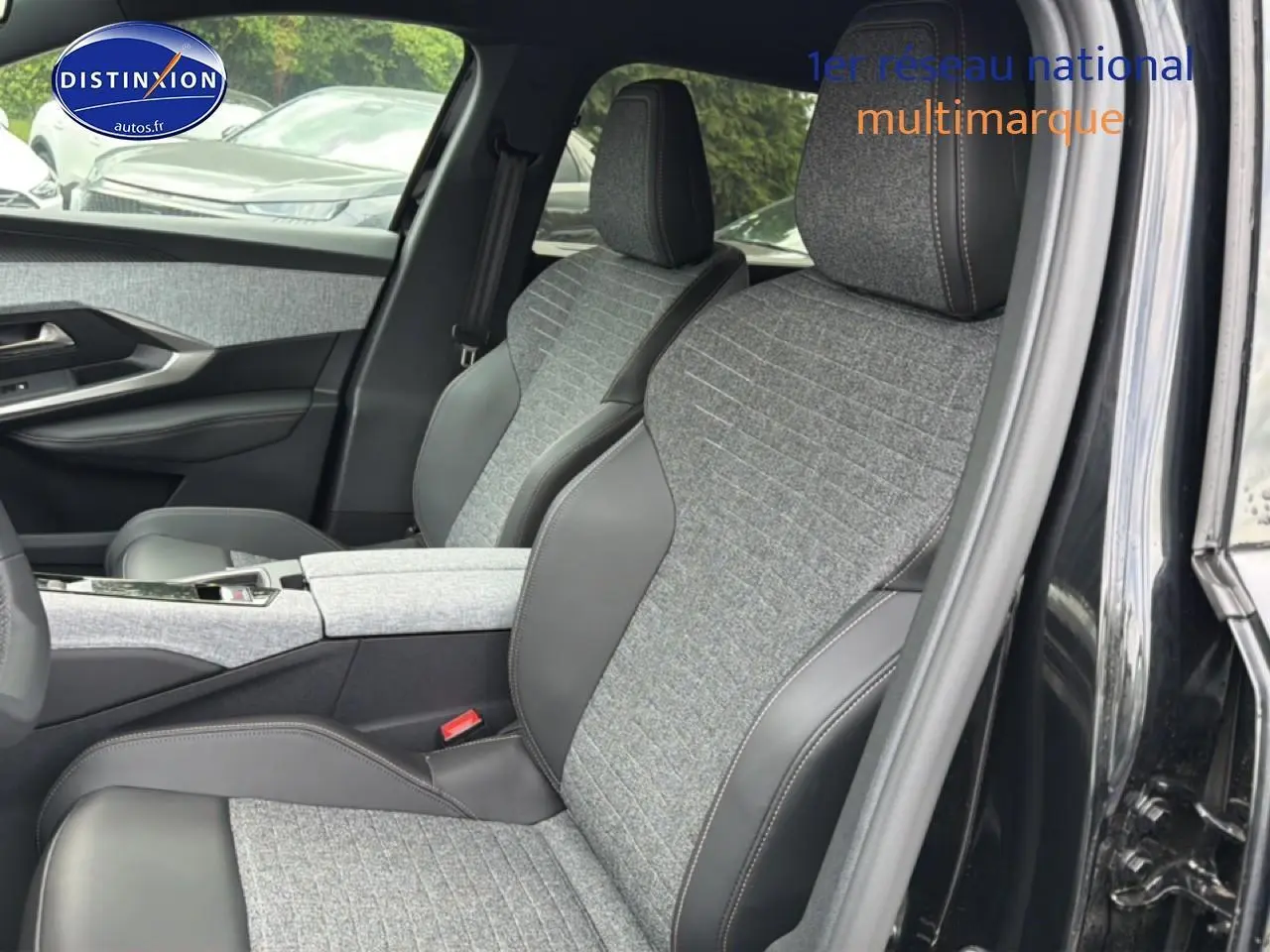 Vue intérieure côté droit du Peugeot 5008 noir 2025, mettant en valeur les sièges en tissu gris et cuir noir avec accoudoir central.
