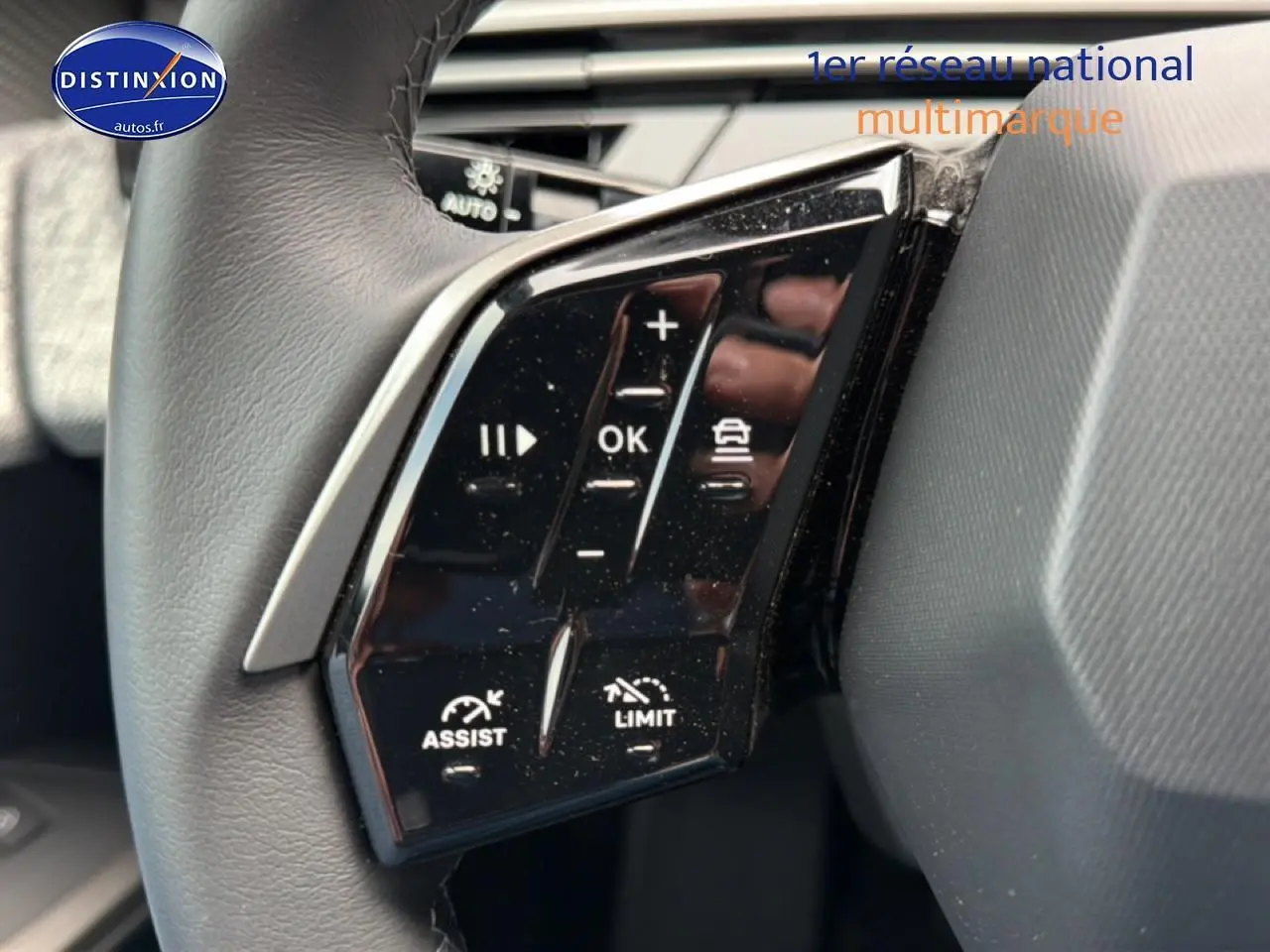 Gros plan sur les commandes multifonctions noires du volant cuir côté gauche du Peugeot 5008 Hybrid 145 allure e-dcs6 noir.