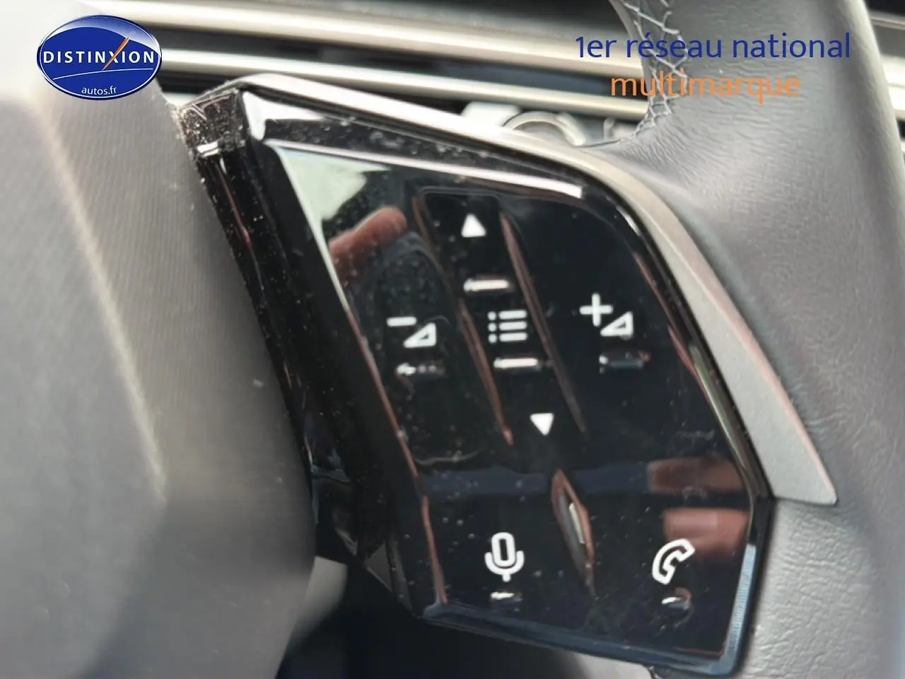 Gros plan sur les commandes vocales et audio au volant cuir du Peugeot 5008 noir, version Hybrid 145 allure e-dcs6.