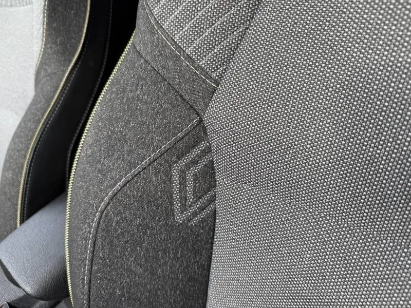 Gros plan sur le tissu gris et noir du siège avant du Renault Captur 2025, avec surpiqûres et motif losange distinctif.