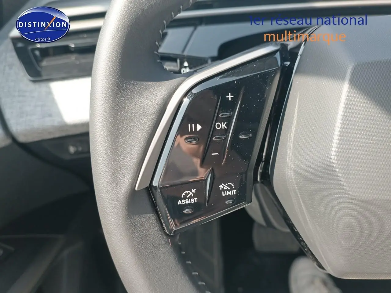 Gros plan sur les commandes au volant cuir noir du Peugeot 5008 gris artense, mettant en valeur les boutons multifonctions.