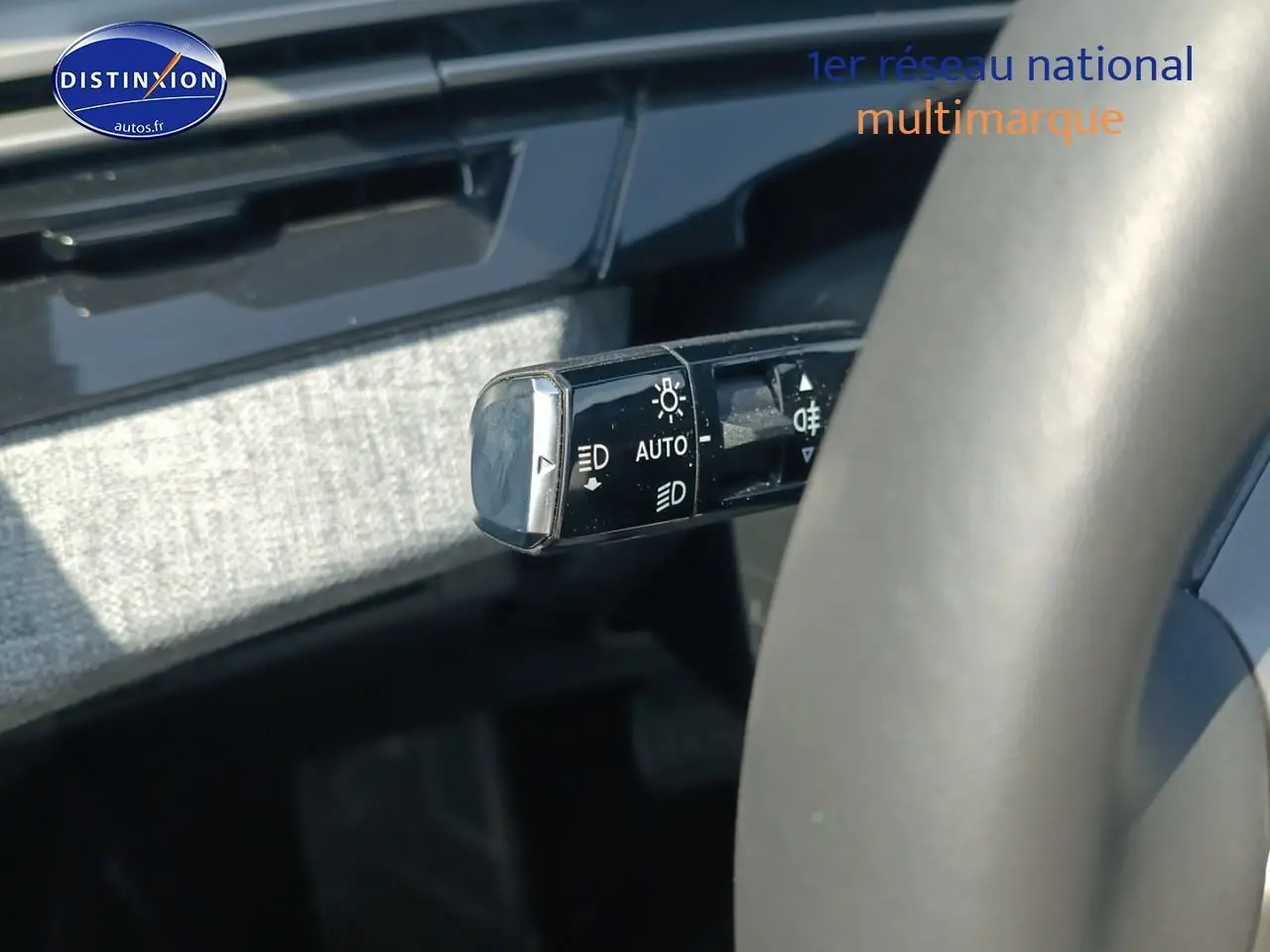 Gros plan sur la commande des phares à gauche du volant d’un Peugeot 5008 gris Artense, intérieur moderne.