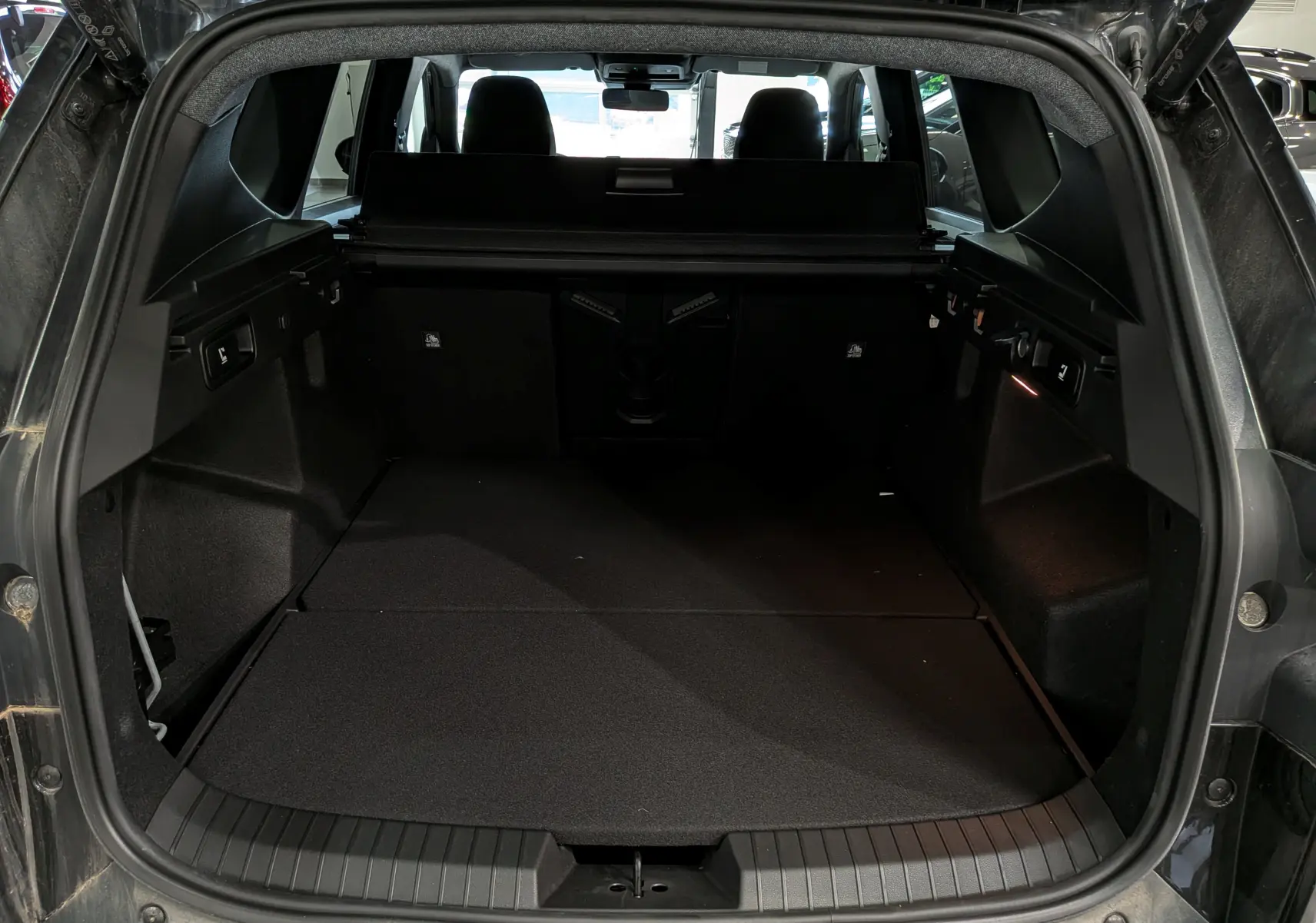 Vue arrière du coffre noir nacré du Dacia Bigster 2026, montrant un espace de chargement spacieux et bien fini.