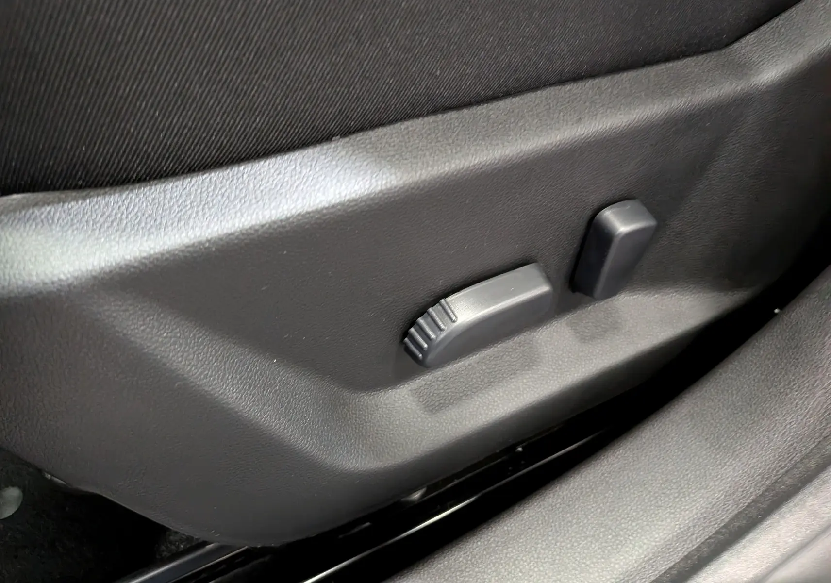 Détail du réglage électrique du siège conducteur sur la porte intérieure noire d’un Dacia Bigster 2026.