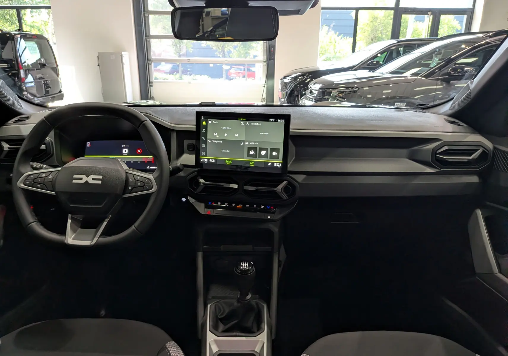 Vue intérieure avant du tableau de bord noir du Dacia Bigster Mild Hybrid avec écran tactile et volant multifonction.
