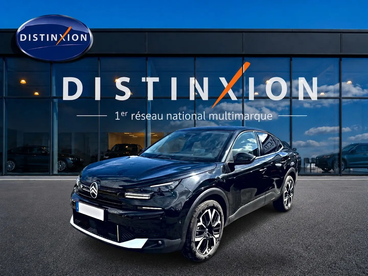 Citroën C4 X noire vue 3/4 avant droit, avec jantes alu distinctives, devant une vitrine Distinxion.