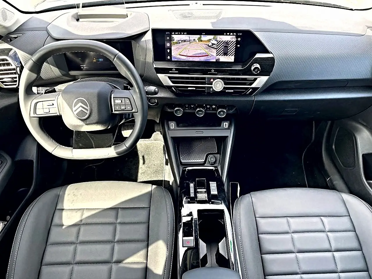 Vue intérieure avant du Citroën C4 X hybride noir 2025, avec tableau de bord moderne et écran tactile affichant la caméra de recul.