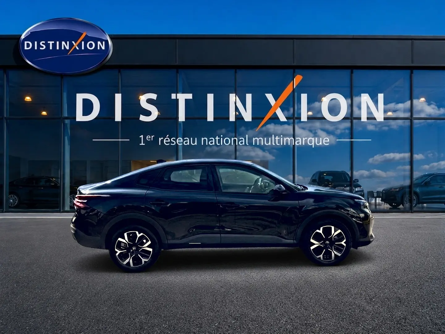 Profil droit de la Citroën C4 X hybride noire 2025, avec jantes alu et lignes fluides devant un showroom Distinxion.